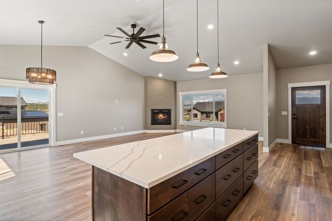 Kitchen featuring open floor plan, light wood-style floors, a ceiling fan, baseboards, and vaulted ceiling | Image 17
