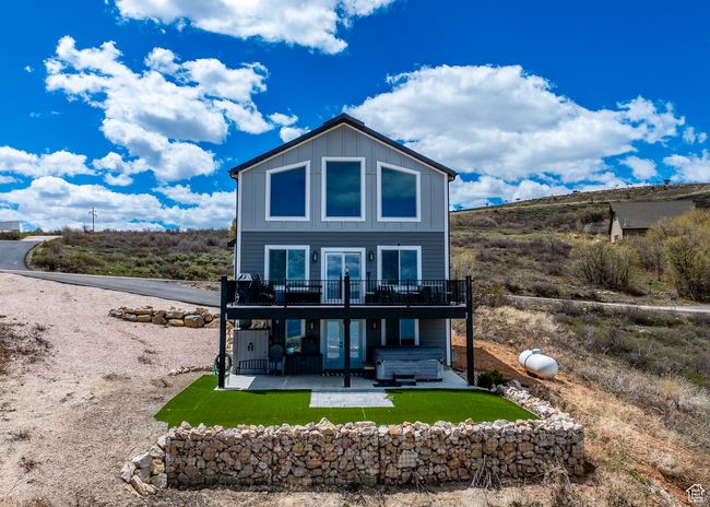 house with a hot tub, a wooden deck, board and batten siding, a patio area, and french doors | Image 6