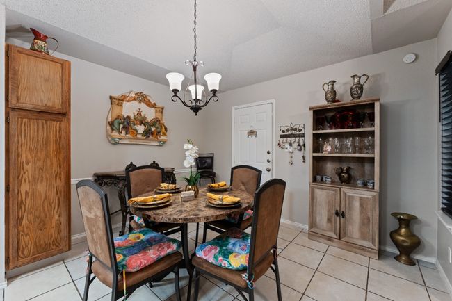 Dining space featuring a chandelier, light tile patterned floors, and a textured ceiling | Image 9