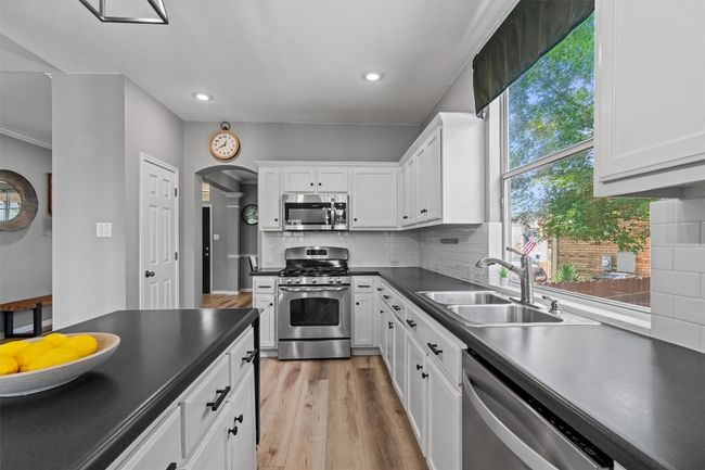 Kitchen featuring appliances with stainless steel finishes, a sink, dark countertops, recessed lighting, and white cabinets | Image 14