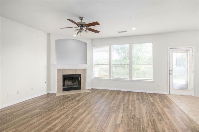 Unfurnished living room featuring ceiling fan, wood finished floors, a tile fireplace, healthy amount of natural light, and recessed lighting | Image 8