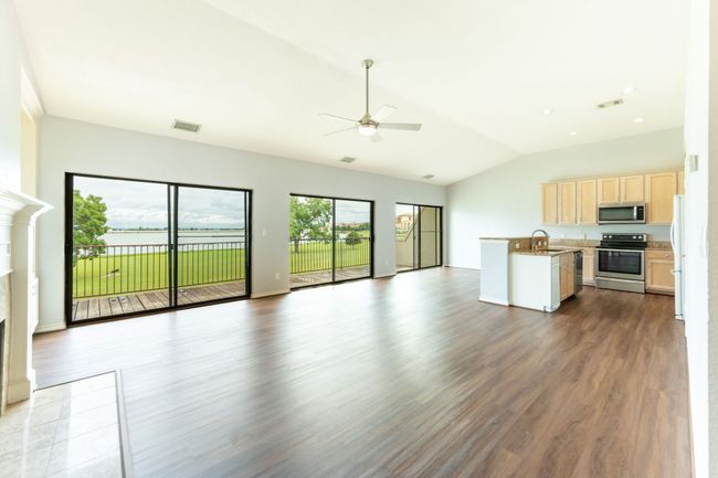 Unfurnished living room featuring lofted ceiling, a ceiling fan, a fireplace, and dark wood finished floors | Image 7