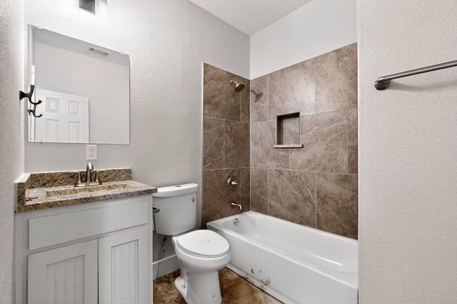 Bathroom featuring vanity, a textured wall, and shower / washtub combination | Image 25