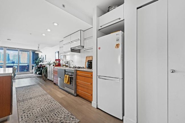 Kitchen featuring white cabinets, light wood-style floors, light countertops, and appliances with stainless steel finishes | Image 11