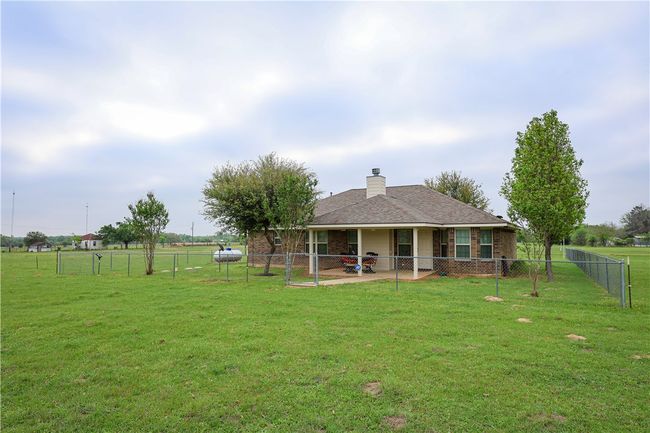 Back of house with a lawn, a chimney, fence, and a patio | Image 13