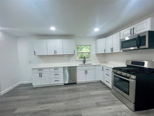 Kitchen with appliances with stainless steel finishes, light countertops, backsplash, white cabinetry, and recessed lighting | Image 4