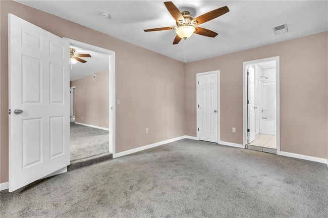 Unfurnished bedroom with a ceiling fan, carpet floors, baseboards, ensuite bath, and visible vents | Image 15