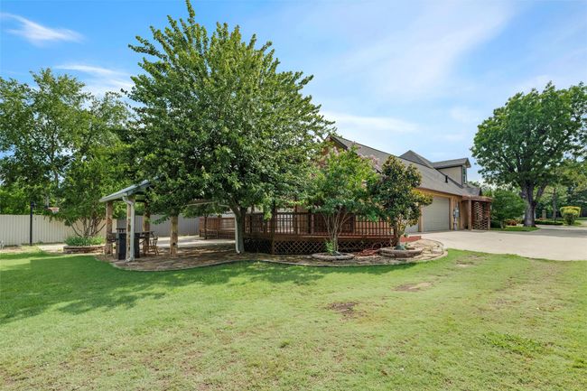 View of property hidden behind natural elements with driveway, a garage, and a deck | Image 32