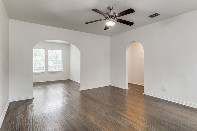 Spare room featuring dark wood-style floors, ceiling fan, and arched walkways | Image 6