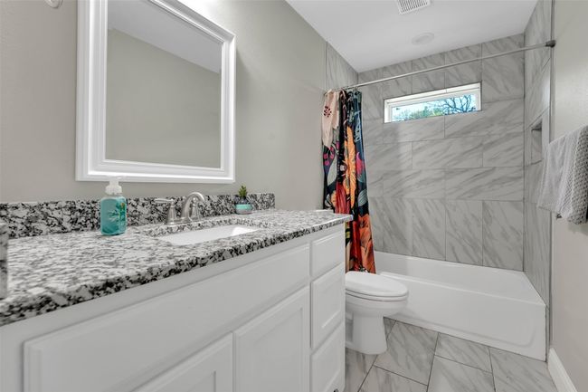Full bath featuring vanity, toilet, visible vents, shower / bath combo with shower curtain, and marble finish floor | Image 29