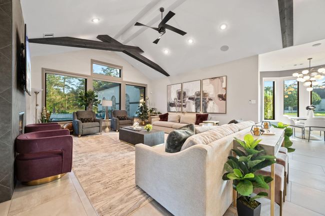 Spacious, modern living room with high ceilings, exposed beams, and large windows offering natural light and scenic views. | Image 25