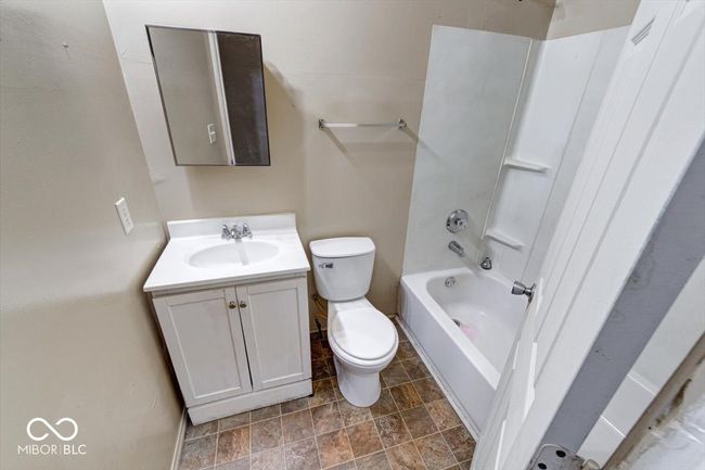 full bathroom featuring toilet, tub / shower combination, vanity, and stone finish flooring | Image 9