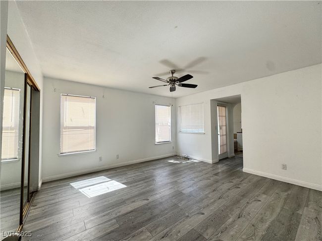 Empty room with dark wood-type flooring, ceiling fan, and baseboards | Image 13