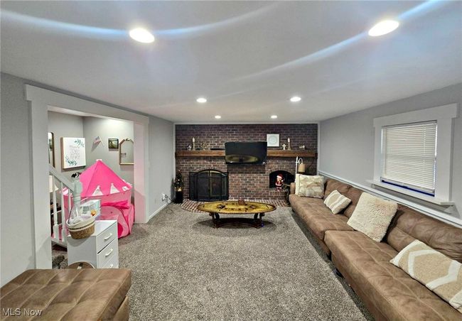 Living area with a brick fireplace, carpet flooring, recessed lighting, and brick wall | Image 26