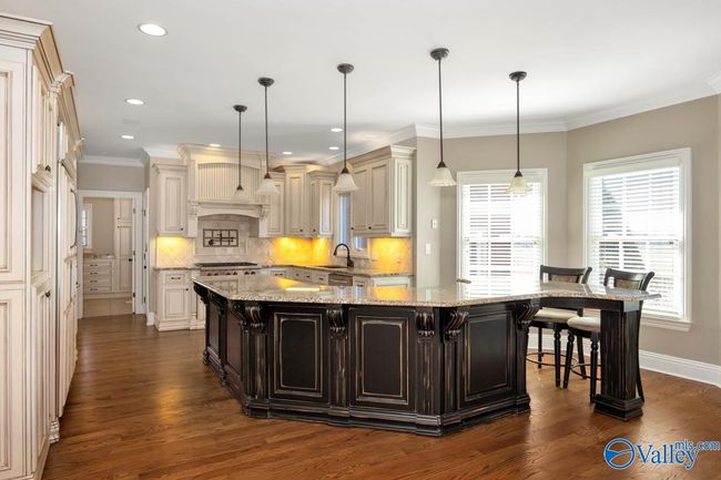 Wood flooring, wood cabinetry, kitchen island with bar seating, recessed lighting | Image 11