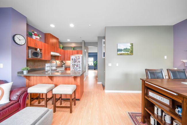 Kitchen featuring a peninsula, a kitchen breakfast bar, stainless steel microwave, light wood-style floors, and under cabinet range hood | Image 15