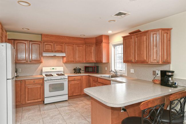 Kitchen featuring light countertops, white appliances, under cabinet range hood, a sink, and visible vents | Image 4