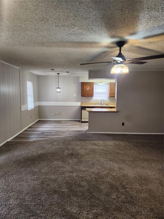 Unfurnished living room with carpet flooring, a sink, ceiling fan, a textured ceiling, and baseboards | Image 6
