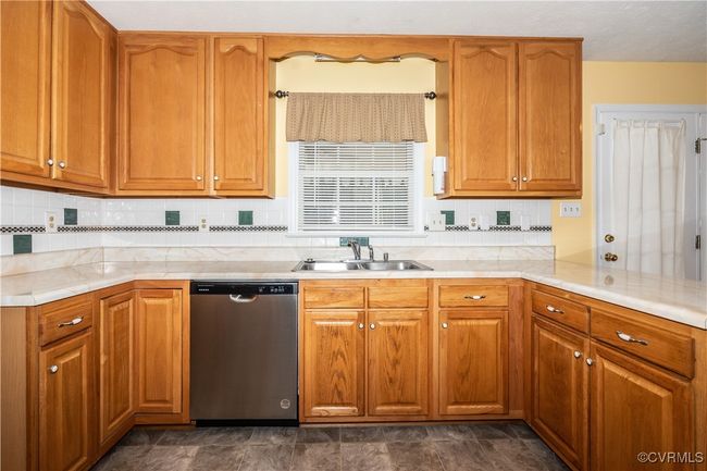 Kitchen featuring dishwasher, light countertops, backsplash, and brown cabinets | Image 9