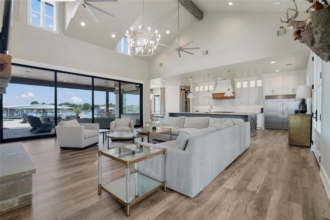 Living area featuring high vaulted ceiling, a ceiling fan, wood finished floors, beamed ceiling, and a large fireplace | Image 25