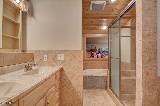 Bathroom with tile walls, a shower stall, a bath, tile patterned flooring, and double vanity | Image 44