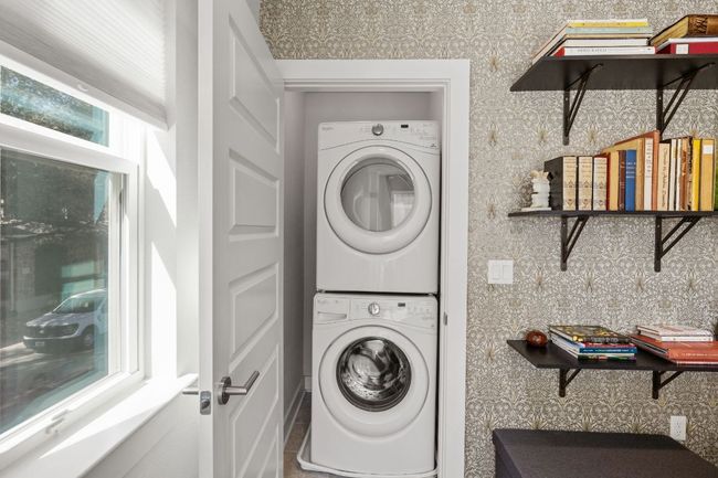 Washroom featuring wallpapered walls, stacked washing maching and dryer, and laundry area | Image 16