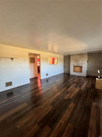 Unfurnished living room featuring a textured ceiling, a fireplace, and dark hardwood / wood-style flooring | Image 2