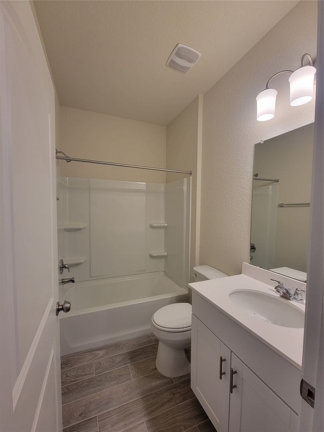 Full bath featuring toilet, vanity, wood tiled floor, visible vents, and a textured wall | Image 12