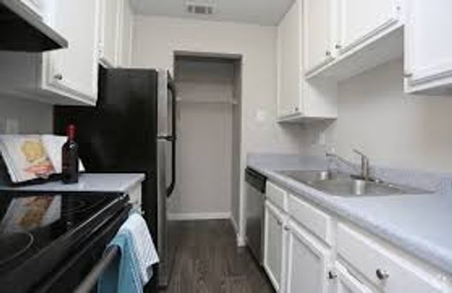 Kitchen with under cabinet range hood, white cabinets, and light countertops | Image 6
