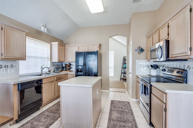 Featuring an abundance of cabinetry and prep space, the island kitchen includes a dedicated pantry and flows directly into the formal dining space for convenience when serving and entertaining. | Image 10