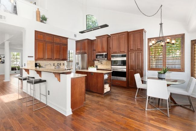Kitchen featuring appliances with stainless steel finishes, a peninsula, dark wood-style flooring, high vaulted ceiling, and crown molding | Image 9