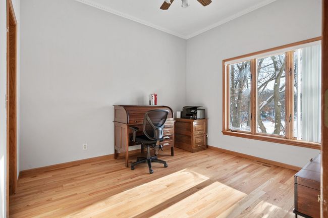 The main level bedroom is spacious and comfortable. It is currently being used as an office. The refinished wood floors are gorgeous, the crown molding adds a touch of character, there is a walk-in closet, and the view of the lake is fantastic! | Image 16