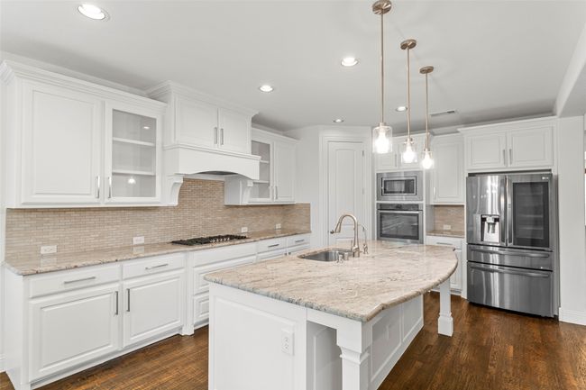 Kitchen featuring a sink, stainless steel appliances, white cabinetry, and dark wood-type flooring | Image 11