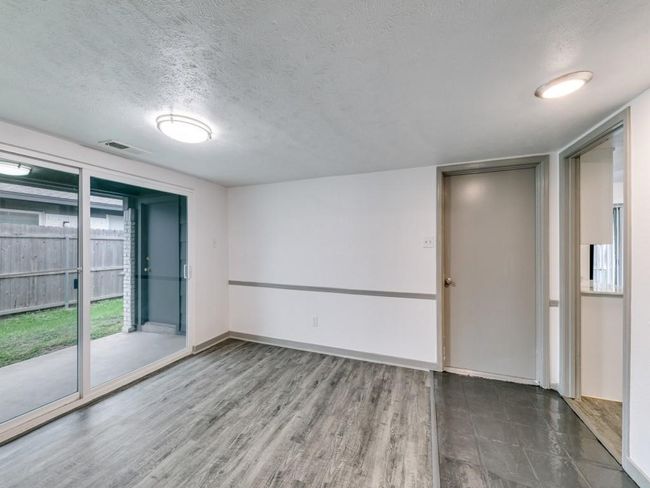 Spare room featuring a textured ceiling, baseboards, and wood finished floors | Image 8