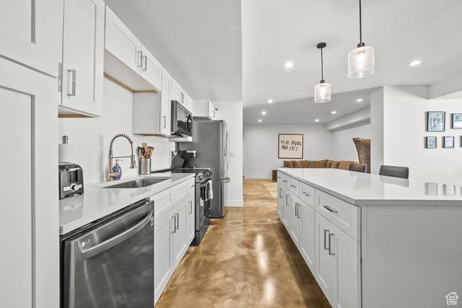 Kitchen with appliances with stainless steel finishes, concrete floors, recessed lighting, light countertops, and white cabinetry | Image 26