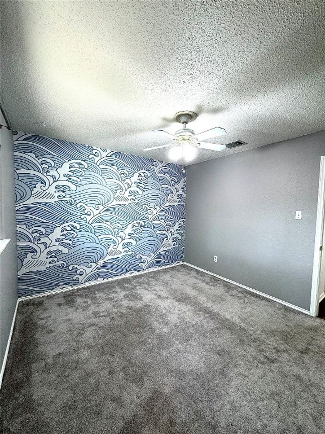 Empty room featuring a textured ceiling, an accent wall, carpet flooring, and ceiling fan | Image 20