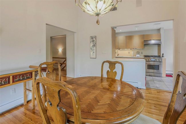 Dining room featuring light wood-type flooring, a towering ceiling, a baseboard heating unit, and a chandelier | Image 14