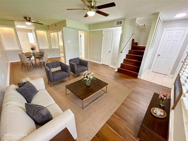 Living room featuring stairway, a ceiling fan, wood finished floors, baseboards, and visible vents | Image 10