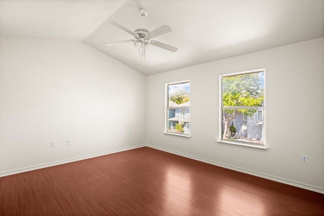 Unfurnished room with dark wood finished floors, lofted ceiling, and a ceiling fan | Image 12