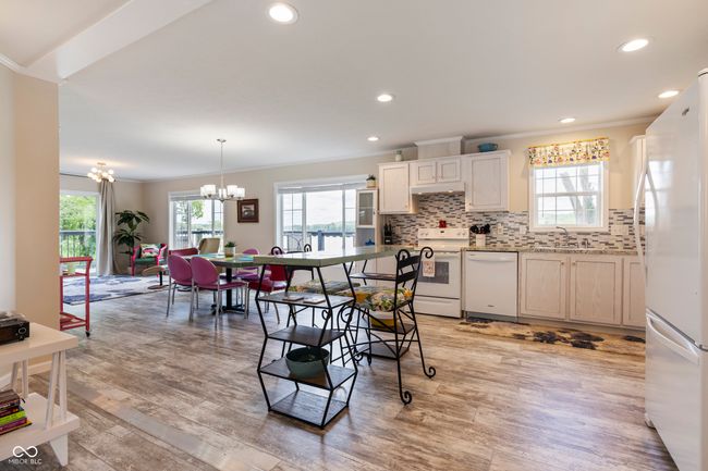 kitchen with white appliances, crown molding, a chandelier, backsplash, and light wood-style flooring | Image 17