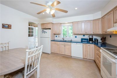 Kitchen with white appliances, light brown cabinetry, backsplash, light tile floors, and sink | Image 3