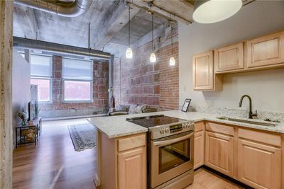 Kitchen with light hardwood / wood-style flooring, stainless steel range with electric cooktop, kitchen peninsula, sink, and light brown cabinets | Image 3