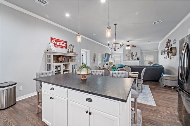 Kitchen featuring a breakfast bar, visible vents, dark countertops, and freestanding refrigerator | Image 15