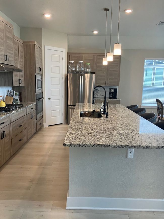 Kitchen featuring wall oven, a sink, refrigerator, cooktop, and extractor fan | Image 5