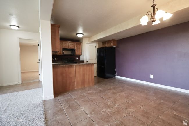 Kitchen with black appliances, dark countertops, a peninsula, and light tile patterned floors | Image 19