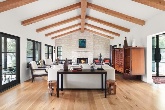 Living room featuring a large fireplace, white oak wood floors, and vaulted ceiling with natural wood beams | Image 15