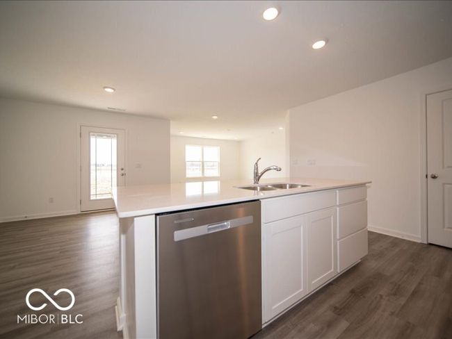 kitchen featuring stainless steel dishwasher, open floor plan, white cabinetry, and a sink | Image 22