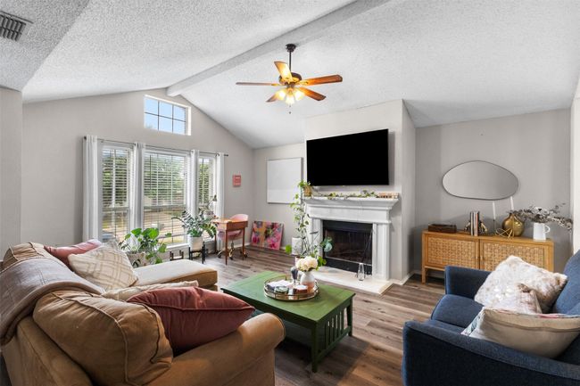 Living room with a ceiling fan, wood finished floors, a fireplace with raised hearth, and a textured ceiling | Image 7