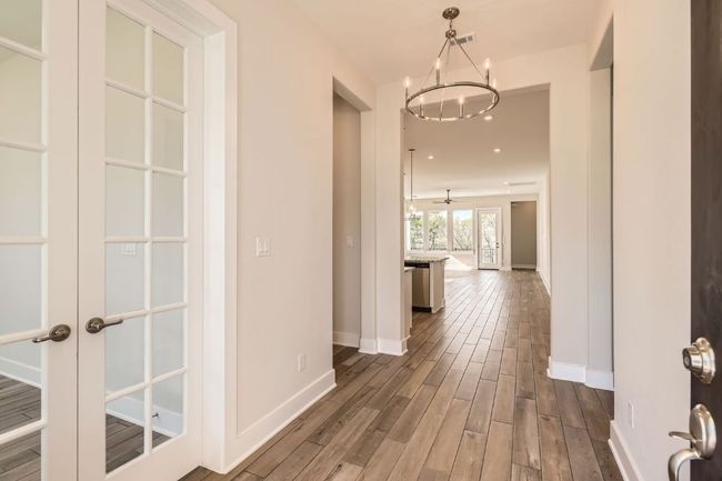 Hallway featuring baseboards, a notable chandelier, french doors, and dark wood-style floors | Image 7