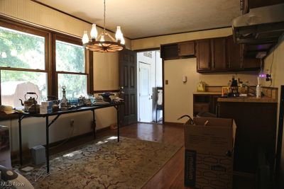 Kitchen with pendant lighting, dark brown cabinets, dark hardwood / wood-style floors, extractor fan, and a notable chandelier | Image 3